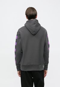 Hanorac gri cu buzunar tip cangur, având modele grafice mov pe mâneci. Textură moale și glugă ajustabilă. Stil minimalist.