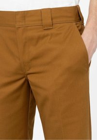 Bruna bomullsbukser med en slät yta, rak front, sidofickor och en bältesloop i midjan. Skräddarsydd passform med rena linjer.