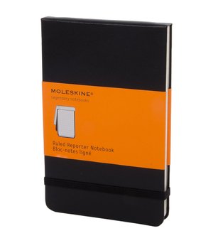 Taccuino Moleskine nero rigato per reporter con angoli arrotondati, chiusura con elastico e etichetta su banda di carta arancione sulla copertina.