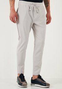 Lichtgrijze joggers met een elastische tailleband en trekkoord. Gemaakt van zacht materiaal, met taps toelopende benen en zijzakken.