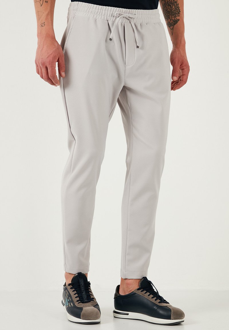 Lichtgrijze joggers met een elastische tailleband en trekkoord. Gemaakt van zacht materiaal, met taps toelopende benen en zijzakken.