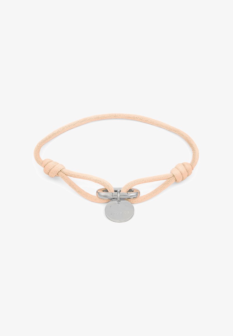 Braccialetto in tessuto color nudo con una chiusura in argento liscia e una targhetta rotonda in metallo con testo in rilievo. Presenta un design annodato per la regolazione.