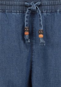 Denim joggers in donkerblauw met een elastische tailleband. Voorzien van een trekkoord met houten kralen en metalen accenten. Gladde textuur.