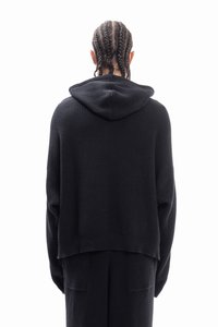 Black hooded sweater with a ribbed texture, loose fit, and dropped shoulders. Simple design with no visible logos or embellishments.