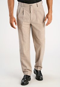 Pantalones de mezcla de lana beige con pliegues frontales, cierre de botón y diseño de pierna recta, combinados con zapatos de cuero negros.
