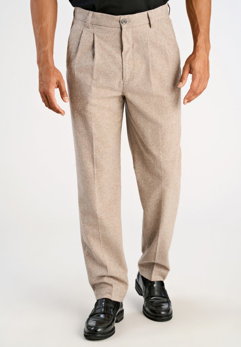 Pantalones de mezcla de lana beige con pliegues frontales, cierre de botón y diseño de pierna recta, combinados con zapatos de cuero negros.