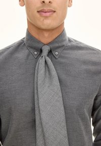 Grijze button-up shirt met eenpuntige kraag en een gestructureerde grijze stropdas. De stof lijkt geweven met subtiele patronen en een gladde afwerking.