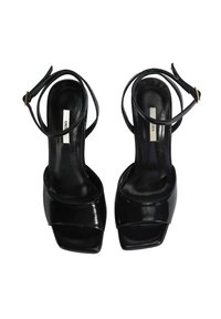 Zwarte gepatenteerde leren sandalen met hoge hak, open teen, brede voorklep en slanke enkelband met een gouden verstelgesp.