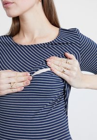 Laivan siniraitainen imetystoppi, jossa on pyöreä pääntie ja huomaamaton päällekkäissuunnittelu, joka esittelee sisäflapin imetyskäyttöön.