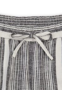 Linjapantot har en svart och vit randig design, en elastisk midja med dragsko och en mjuk, texturerad yta.