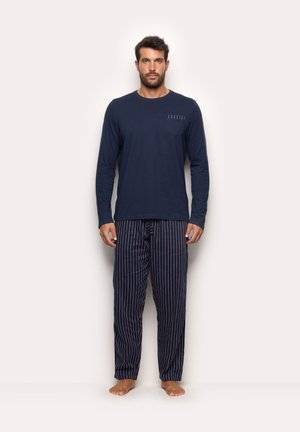 Chemise à manches longues navy avec une poche poitrine et cinq rayures accentuées ; associée à un pantalon de pyjama rayé dans des couleurs similaires navy et blanc.