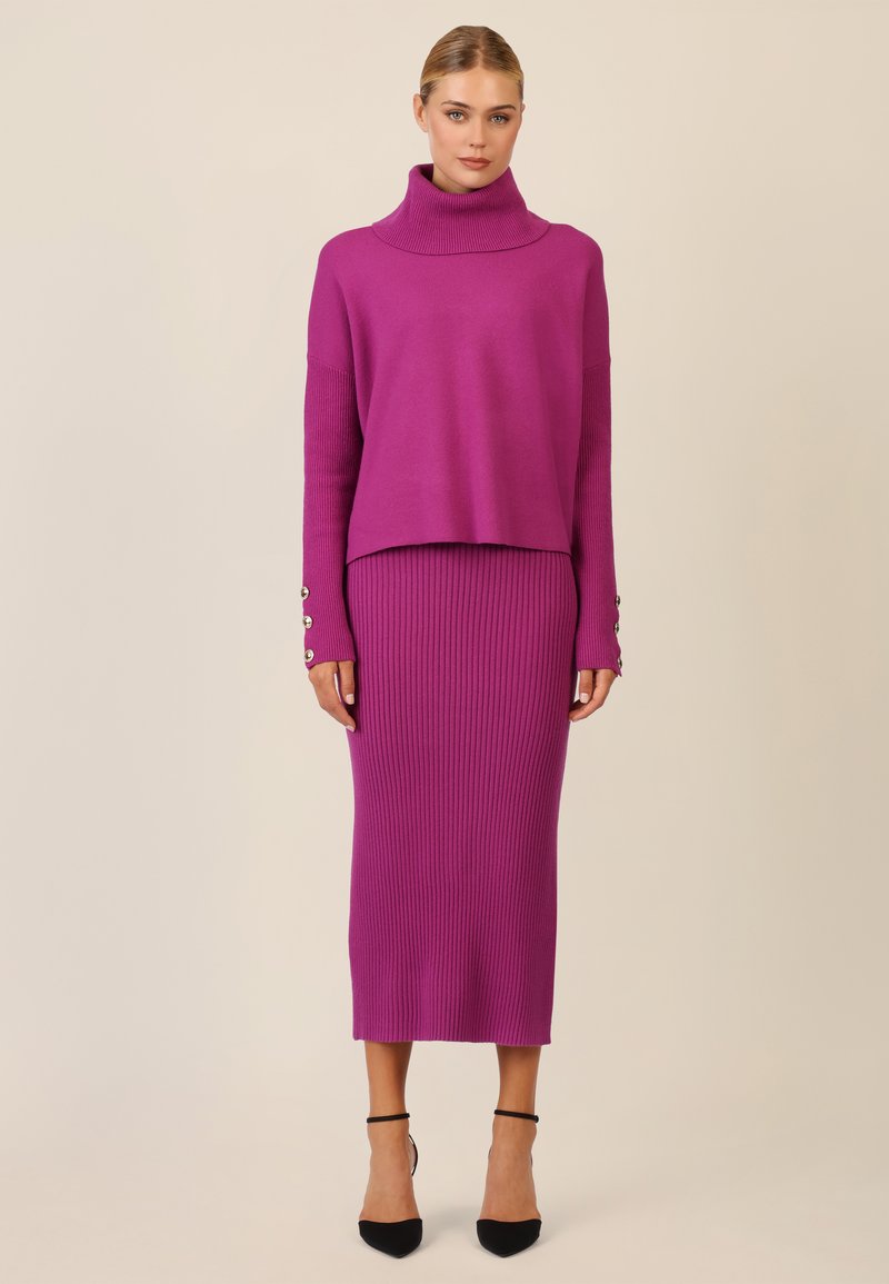 Langärmliger Rollkragenpullover und geripptes Midi-Rock-Set in lebhaftem Magenta. Der Rock weist eine körperbetonte Silhouette auf, mit Knopfdetails an den Ärmeln.
