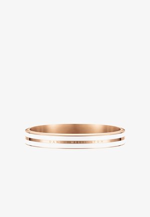 Auksinės spalvos metalinė apyrankė su balto emalio juostelėmis. Pasižymi lygiu paviršiumi ir išraitytu užrašu "DANIEL WELLINGTON" išorinėje pusėje.