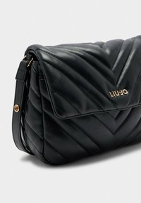 Borsa a spalla in pelle trapuntata nera con pattina, logo "LIU JO" in tonalità oro e tracolla regolabile con hardware in tonalità oro.