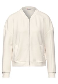 Chaqueta bomber con cremallera en color beige claro, confeccionada en una suave y lisa mezcla de algodón. Cuenta con bolsillos laterales, puños acanalados y un diseño minimalista.