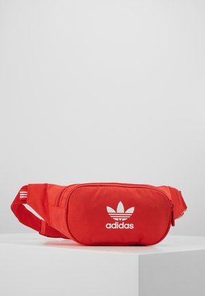 Czerwona torba na biodra z zamkiem błyskawicznym, z białym logo Adidas i trzema białymi paskami na regulowanym pasku. Gładka tekstura.