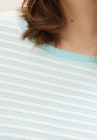 Ljusblå randig topp med vita texturerade ränder, med en ribbad halsringning. Det mjuka tyget ger en slät yta och en bekväm passform.