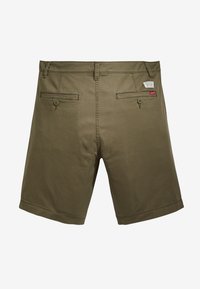Shorts vert olive avec deux poches arrière, passants de ceinture et un patch logo sur la taille. Fabriqués en tissu léger avec une texture lisse.