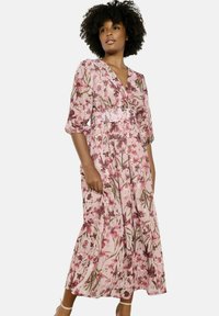 Bloemrijke maxi-jurk in zachte roze stof met driekwartmouwen, een V-hals, en een aansluitende taille, gekenmerkt door een délicate afdruk van roze en groene bloemen.