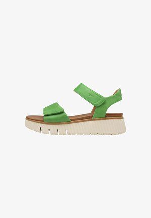 Groene leren sandalen met dubbele verstelbare banden, een leren voetbed in tan kleur en een dikke witte rubberen zool met verticale ribbels.