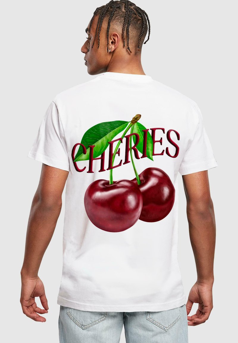 Hvid t-shirt med stort grafisk tryk af røde kirsebær og grønne blade, med "CHERIES" tekst i fed rød skrift på ryggen.