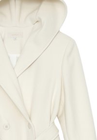 Cappotto bianco doppiopetto con un ampio cappuccio, tessuto testurizzato e cintura. Presenta dettagli con bottoni sul davanti.