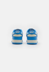 Plave kožne Nike tenisice s teksturiranim mrežastim detaljima, podstavljenim jezikom i kremastom potplate. Sadrže "Nike" oznaku na peti.