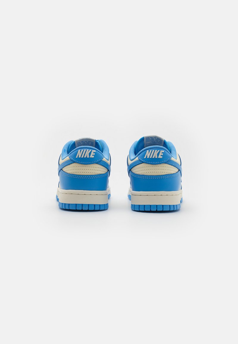 Zapatillas Nike de cuero azul con acentos de malla texturizada, lengüeta acolchada y suela media de color crema. Presenta el logo de 'Nike' en el talón.