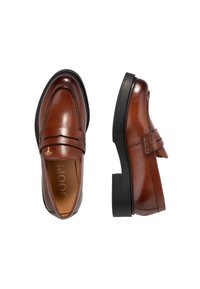 Mocassins en cuir marron avec une finition lisse, présentant une double couture sur le dessus et une bande d'accent surélevée. Semelle extérieure en caoutchouc noir et logo visible à l'intérieur.