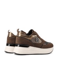 Sneaker in suede marrone con dettagli metallici dorati, suola spessa bianca, punta tonda e un dettaglio con il marchio sul lato. Texture morbida con colori a contrasto.