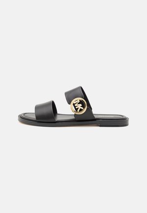 Sort flad sandal med to remme, med en gylden cirkulær logo-spænde på den øverste rem og en tynd sål.