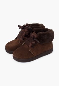 Stivaletti in suede marrone con fodera in pelliccia sintetica e fiocchi in raso scuro sul davanti. Suola in gomma piatta e dettagli cuciti lungo i lati.