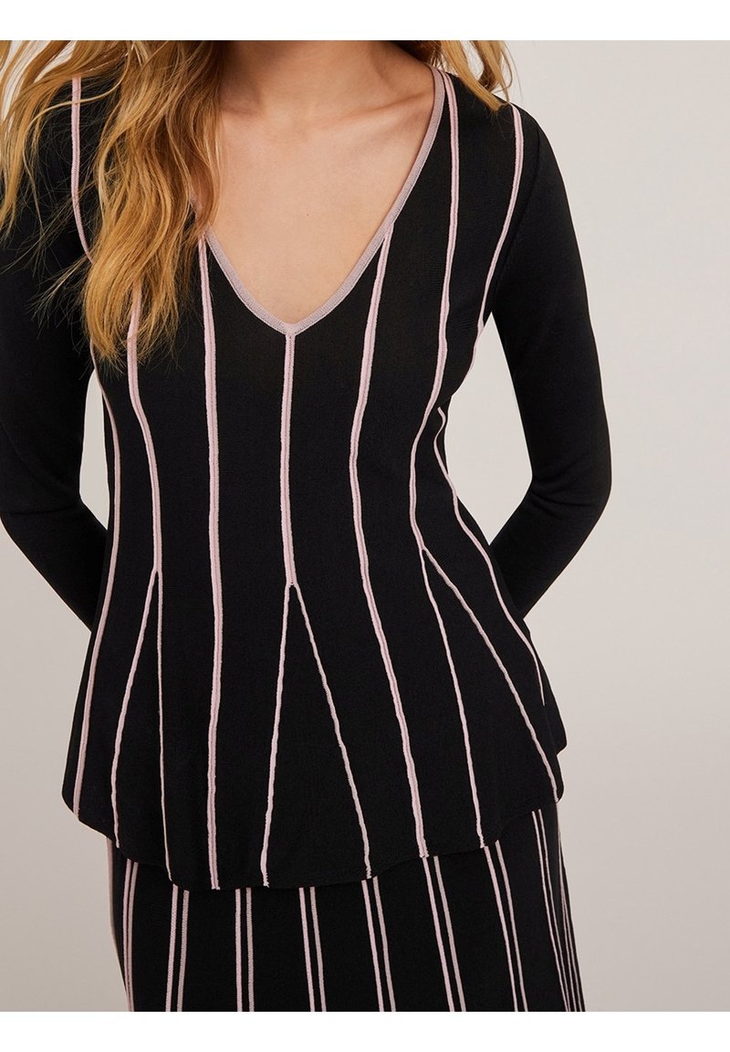 Musta neulepaita, jossa on pystysuoria vaaleanpunaisia raitoja, V-pääntie ja pitkät hihat, hieman levenevä helma ja sileä pinta.