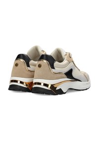 Sneaker beige e nere con un mix di materiali scamosciati e sintetici. Presentano un accento metallico dorato sul tallone e una suola in gomma bianca.