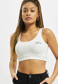 White cropped tank top made of ribbed fabric, featuring a rounded neckline and a gathered hem with black script logo on the front.