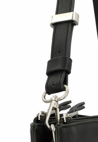 Cinturino in pelle nera con finitura texturizzata, dotato di accessori in argento e di un gancio metallico, attaccato a un compartimento con cerniera.