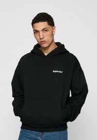 Čierna mikina s kapucňou vyrobená z bavlnenej zmesi, s prednou vreckom, rebrovanými manžetami a logom potlačeným na hrudi. Klasický strih s nastaviteľnou kapucňou.