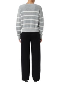 Pull en tricot rayé gris et blanc avec un col rond et des poignets côtelés, associé à un pantalon large noir. Design simple et texturé.