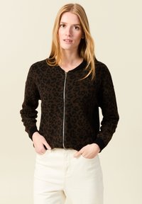 Brun leopardmönstrad zip-up cardigan med ribbad svart krage och manschetter. Har långa ärmar och en figurnära passform. Matchas med ljusa byxor.