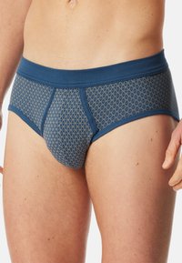 Navy blauwe katoenen slips met een geometrisch patroon in goud. Voorzien van een zachte tailleband en een ondersteunende voorkant. Regular fit.