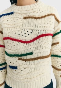 Cremfarbener gestrickter Pullover mit strukturierten Mustern und horizontalen, erhöhten Garnstreifen in Rot, Grün, Braun und Blau, getragen von einer Person.
