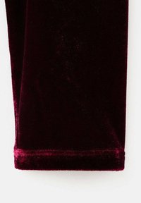 Tessuto di velluto borgogna con una consistenza liscia, dotato di un bordo orlato. Il materiale presenta una leggera lucentezza e un colore ricco e profondo.