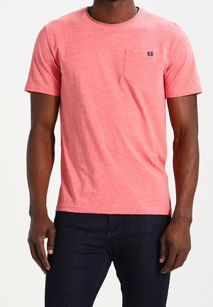 Koszulka z krótkim rękawem i okrągłym dekoltem w jaskrawym koralowym kolorze, z małą kieszonką na piersi i delikatną fakturą, w połączeniu z ciemnoniebieskimi dżinsami.