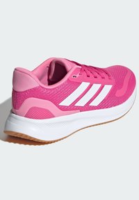 Baskets de sport rose vif avec un dessus en mesh, trois bandes blanches, un col rembourré et une semelle en caoutchouc texturé pour l'adhérence.
