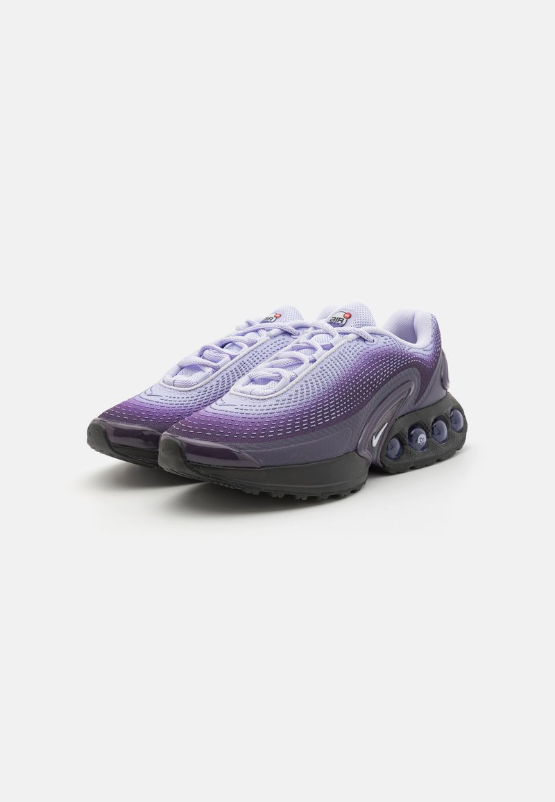 Fioletowe buty sportowe z gradientem, z siateczkową cholewką i wyraźną podeszwą z poduszką powietrzną. Posiadają czarną gumową podeszwę oraz kontrastujące białe sznurowadła.