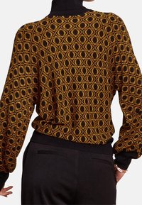 Braun- und schwarz gemusterter Pullover mit Ballonärmeln und eng anliegenden Bündchen, der ein geometrisches Design aufweist.