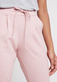 Ljust rosa sweatpants i mjukt tyg, med dragsko i midjan, sidofickor och en avslappnad passform. Slät textur med subtila sömnadsdetaljer.
