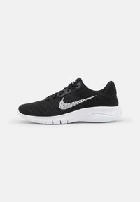 Scarpe da ginnastica nere con una tomaia in mesh traspirante, lacci piatti, logo Nike bianco, e suola curva bianca con scanalature per la flessibilità.