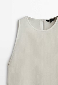 Haut sans manches en maille beige clair avec une texture côtelée, un col arrondi et une fermeture par boutons dans le dos.