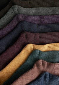 Gestreifte Socken in verschiedenen Farben, darunter Braun, Grau, Lila, Grün und Gold, die Texturen und Dicke variieren.